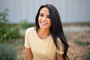 Woman in yellow shirt sitting outside and smiling